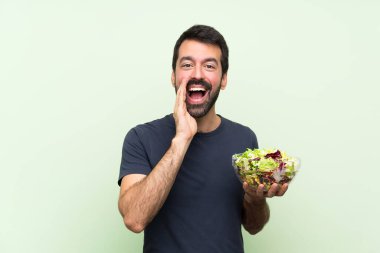 Yeşil duvarın üstünde salatalı yakışıklı genç adam bağırıyor ve bir şeyler söylüyor.