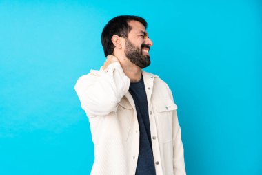 Beyaz kadife ceketli yakışıklı genç bir adam izole edilmiş mavi bir arka planı ve boyun ağrısı var.