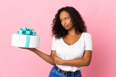 Pasta şefi elinde büyük bir pasta tutuyor. Üzücü bir ifadeyle pembe arka planda izole edilmiş.