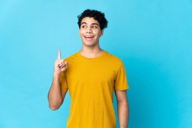 Genç Venezuelalı bir adam mavi arka planda izole edilmiş.