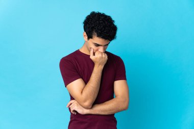 Genç Venezuelalı bir adam mavi arka planda izole edilmiş.