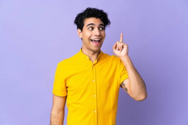 Genç Venezuelalı adam mor arka planda izole edilmiş. Çözümü bulmak için parmağını kaldırıyor.