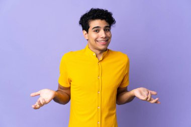 Genç Venezuelalı adam mor arka planda izole edilmiş mutlu ve gülümsüyor.