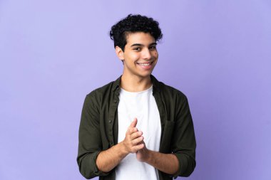 Genç Venezuelalı bir adam mor arka planda izole edilmiş bir konferansta sunumdan sonra alkışlıyor.