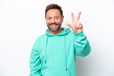Beyaz arka planda izole edilmiş orta yaşlı beyaz adam mutlu ve parmaklarıyla üçe kadar sayıyor.