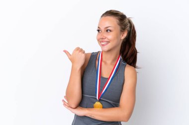 Beyaz arka planda madalyaları olan genç Rus kız bir ürün sunmak için kenarı işaret ediyor.