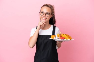 Restoran garsonu. Elinde waffle tutan Rus kız. Pembe arka planda izole edilmiş.