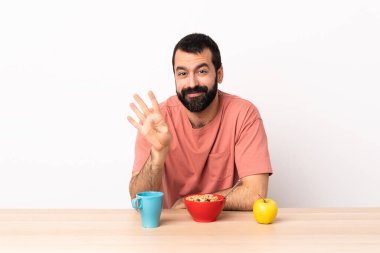 Kafkasyalı bir adam kahvaltısını mutlu yapıyor ve parmaklarıyla dört tane sayıyor..