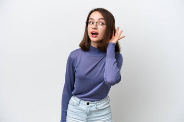 Genç Ukraynalı bir kadın beyaz arka planda izole edilmiş bir şekilde elini kulağına koyarak bir şeyler dinliyor.