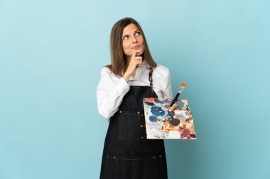 Genç sanatçı Slovak kadın mavi arka planda izole edilmiş ve yukarı bakıyor