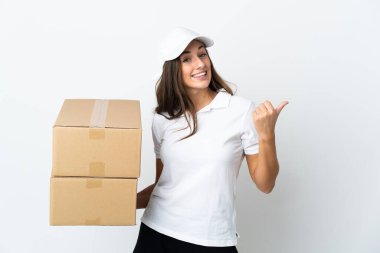 İzole edilmiş beyaz arka planda genç teslimatçı kadın bir ürün sunmak için kenarı işaret ediyor.