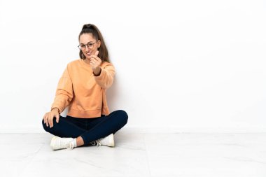 Genç bir kadın yerde oturmuş para hareketi yapıyor.