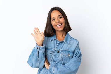 Beyaz arka planda izole edilmiş genç Latin kadın mutlu bir ifadeyle selamlıyor.