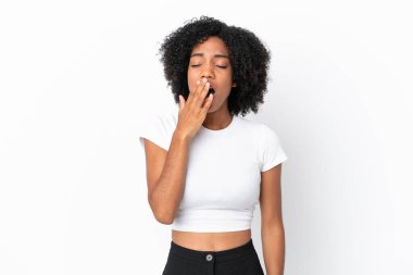 Genç Afrikalı Amerikalı bir kadın beyaz arka planda izole edilmiş esniyor ve ağzını eliyle açık tutuyor.