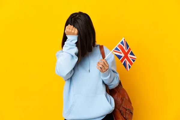 stock image Young latin woman holding an United Kingdom flag isolated on yellow background with headache