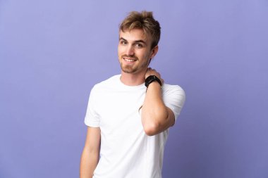 Genç yakışıklı sarışın adam mor arka planda yalnız gülüyor.