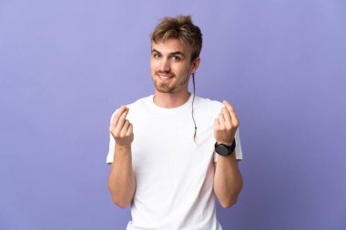 Mor arka planda izole genç sarışın adam para hareketi yapıyor.