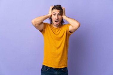 Mor arka planda izole edilmiş genç yakışıklı adam gergin hareketler yapıyor.