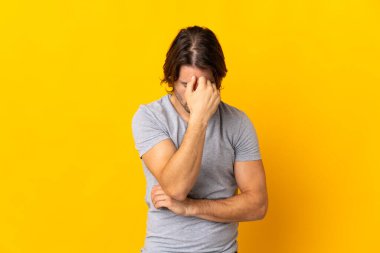 Sarı arka planda başağrısı olan yakışıklı genç bir adam.