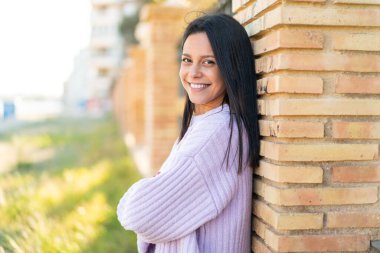 Dışarıda kolları bağlı ve ileriye bakan genç bir kadın.