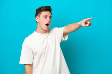 Genç ve yakışıklı Brezilyalı bir adam mavi arka planda izole edilmiş.