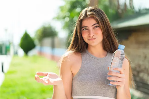 Stock image Young pretty caucasian woman with a bottle of water at outdoors making doubts gesture while lifting the shoulders