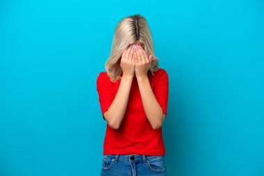 Genç Rus kadın mavi arka planda izole edilmiş, yorgun ve hasta bir ifadeyle.