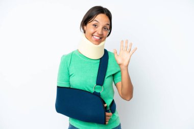 Boyunluk takan ve askı takan genç İspanyol kadın beyaz arka planda izole edilmiş mutlu bir ifadeyle selam veriyor.