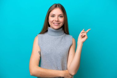 Genç Litvanyalı kadın mavi arka planda izole edilmiş, mutlu ve dik duruyor.