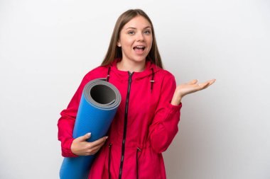 Beyaz arka planda izole edilmiş beyaz bir altlığı olan genç beyaz bir kadın parmak göstererek bir ürün sunuyor.