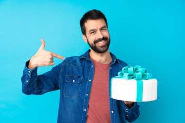 Büyük pastası olan genç yakışıklı bir adam soyutlanmış mavi arka plan gururlu ve kendini beğenmiş