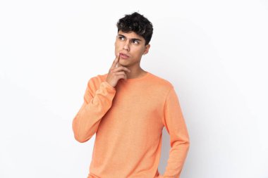 İzole edilmiş beyaz arka planı olan genç bir adam yukarı bakarken şüphe duyuyor.