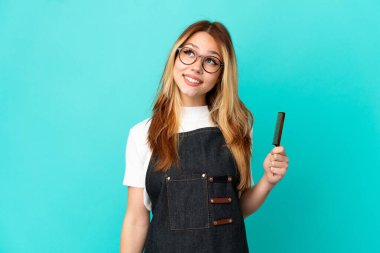 Genç kuaför kız izole edilmiş mavi arka planı araştırırken bir fikir düşünüyor.