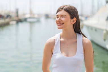 Genç, güzel bir kadın açık havada, mutlu bir ifadeyle.