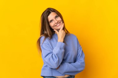 Sarı arka planda izole edilmiş genç Slovak kadın mutlu ve gülümsüyor.