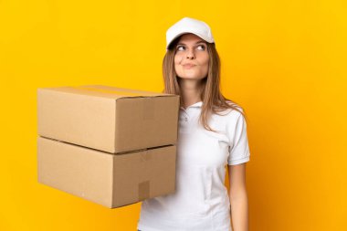 Genç Slovak teslimatçı kadın sarı arka planda izole edilmiş ve yukarı bakıyor