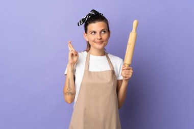 Aşçı Slovak kadın mor arka planda izole edilmiş, parmakları çapraz ve en iyisini diliyor.