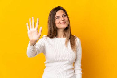 Sarı arka planda izole edilmiş genç Slovak kadın parmaklarıyla beşi sayıyor