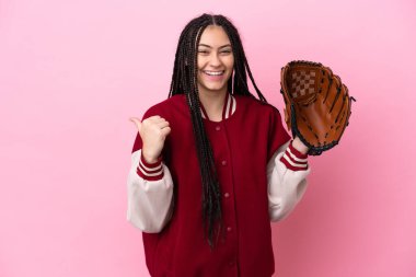 Pembe arka planda izole edilmiş beyzbol eldivenli genç oyuncu bir ürünü sunmak için kenarı işaret ediyor