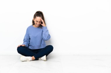 Genç bayan yerde oturmuş gülüyor.