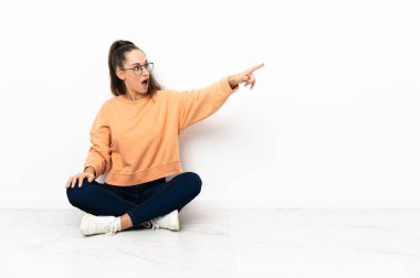 Genç bir kadın yerde oturmuş işaret ediyor.