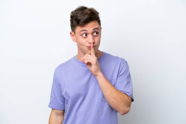 Beyaz arka planda izole edilmiş genç, yakışıklı Brezilyalı bir adam sessiz bir jest işareti gösteriyor. Parmağını ağzına sokuyor.