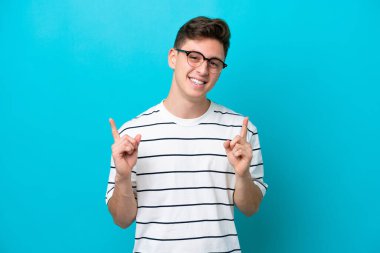 Young handsome Brazilian man isolated on blue background pointing up a great idea