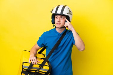 Sırt çantalı genç Brezilyalı adam sarı arka planda izole edilmiş. Şüpheleri ve düşünceleri var.