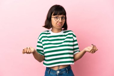 Pembe arka planda soyutlanmış genç melez bir kadın omuzlarını kaldırırken şüpheyle hareket ediyor.