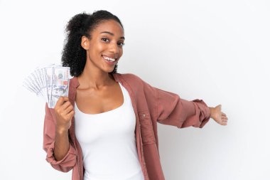 Genç Afrikalı Amerikalı bir kadın, beyaz arka planda izole edilmiş bir sürü para alıyor. Gelmesi için elini uzatıyor.