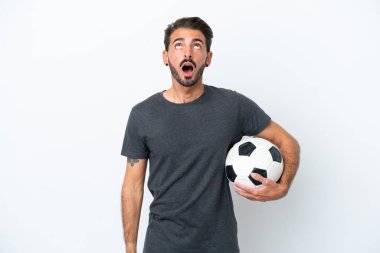 Genç futbolcu kadın beyaz arka planda izole edilmiş yukarı bakıyor ve şaşırmış bir ifadeyle