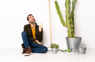 Bahçıvan yerde oturuyor ve harika bir fikri işaret ediyor.