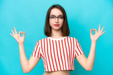 Genç Ukraynalı kadın Zen pozunda mavi arka planda izole edilmiş.