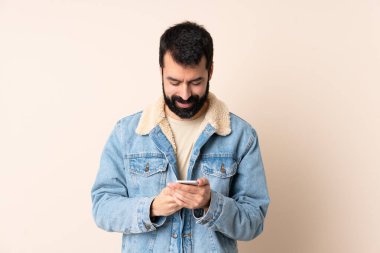 İzole edilmiş arka planda sakallı beyaz bir adam cep telefonuyla mesaj gönderiyor.